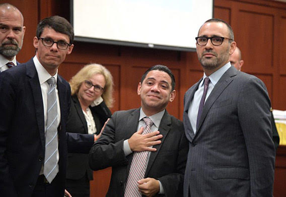 Clemente Aguirre and his legal team stand in court. Clemente smiles with his hand over his heart.